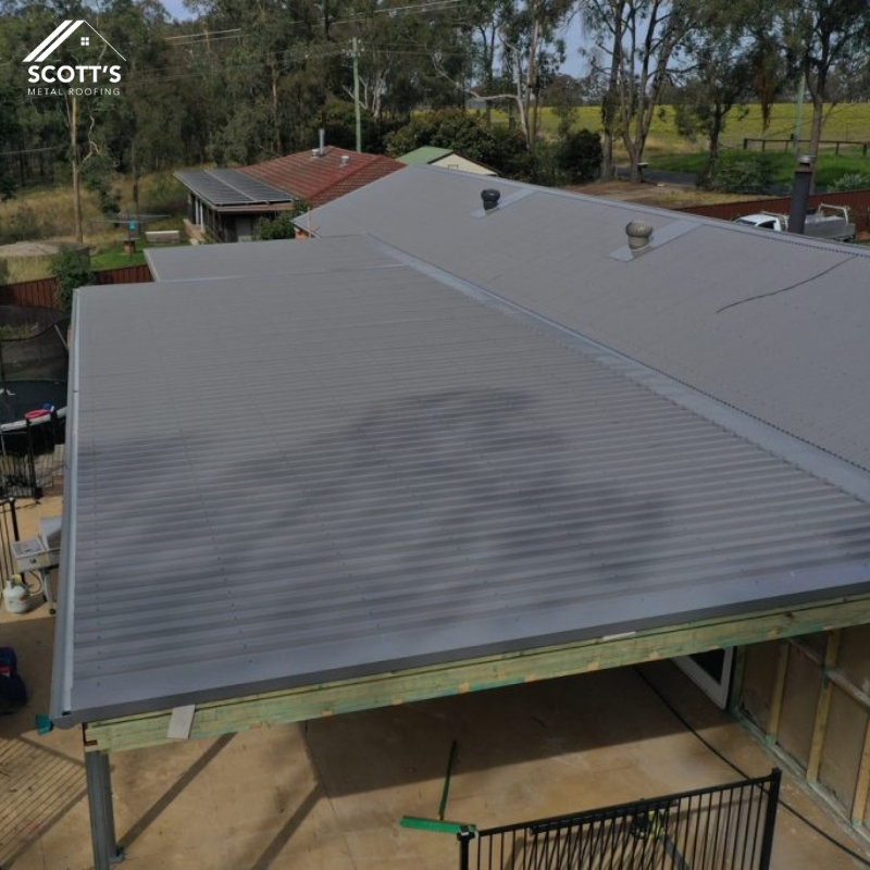 Aerial view of a house with newly installed residential metal roofing, featuring a sleek grey finish and durable construction.