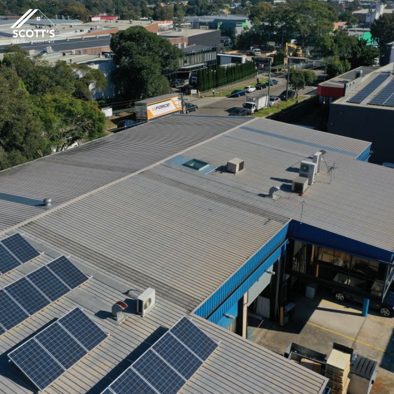 Durable commercial metal roofing with solar panels and ventilation systems on an industrial property, completed by Scott's Metal Roofing.