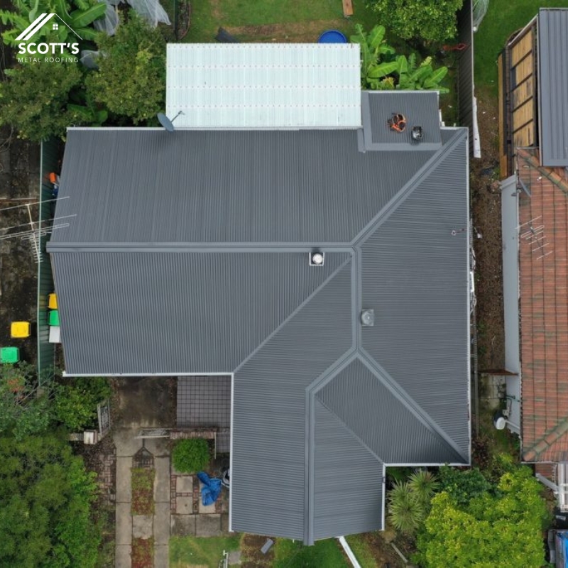 Aerial view of a house with newly installed residential metal roofing, featuring a sleek grey finish and durable construction.