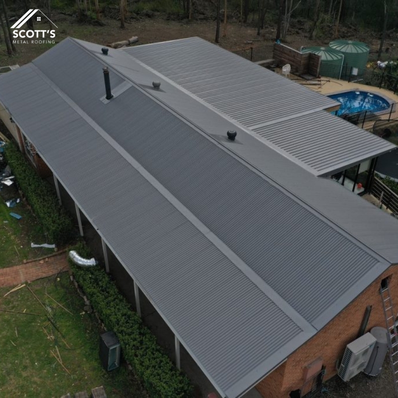 Aerial view of a modern metal roof extension on a residential home, featuring durable steel sheets and ventilation pipes.