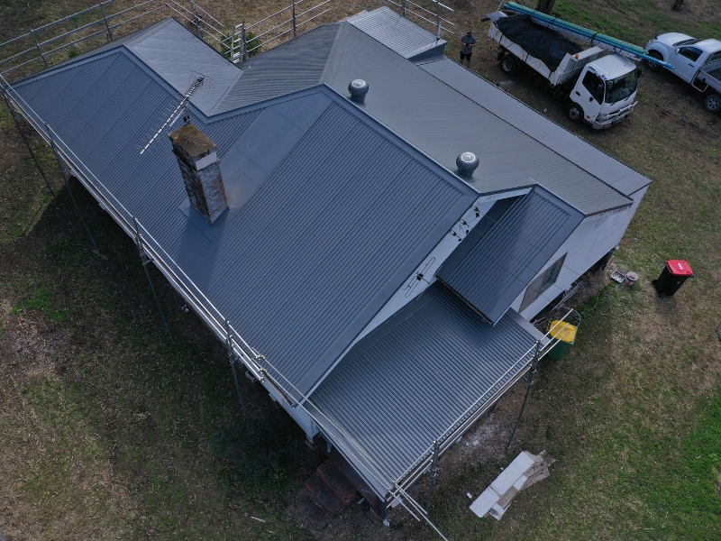 Side view of a ventilated metal roof with whirlybirds and ridge vents for effective ventilation.