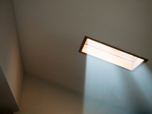 Sunlight streams through a rectangular skylight placement in a white ceiling, casting a bright beam.
