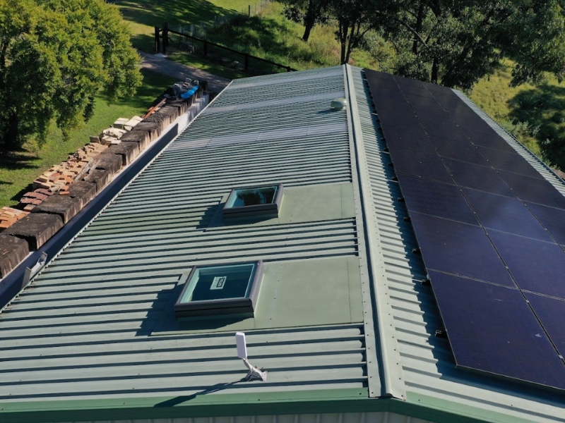 Adding a skylight to a metal roof beside solar panels for improved natural lighting and comfort.