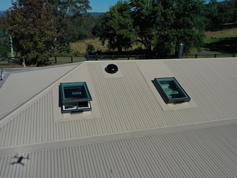 Dual skylight units on metal roof illustrating best practices for adding a skylight with proper sealing and placement.