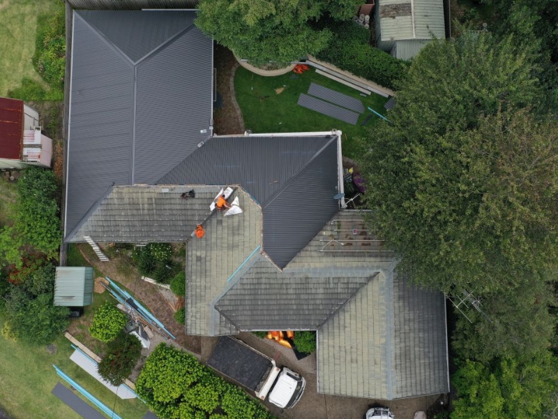 Metal roof installation guide in use during large home roofing project with visible workers.