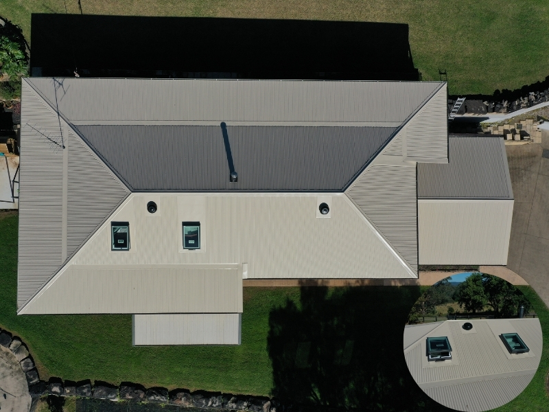 Installing a skylight on a beige metal roof with dual skylights and venting pipes visible from above