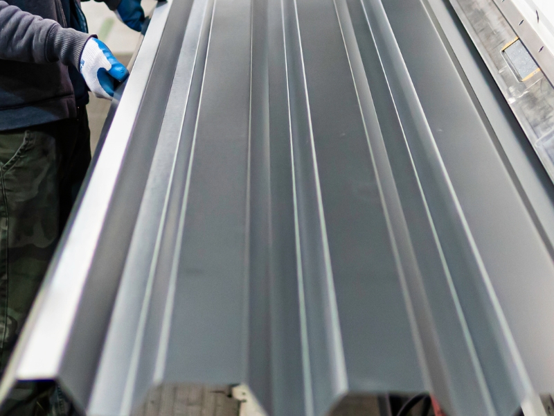 Technician preparing panel before installing sheet metal roofing in a workshop.